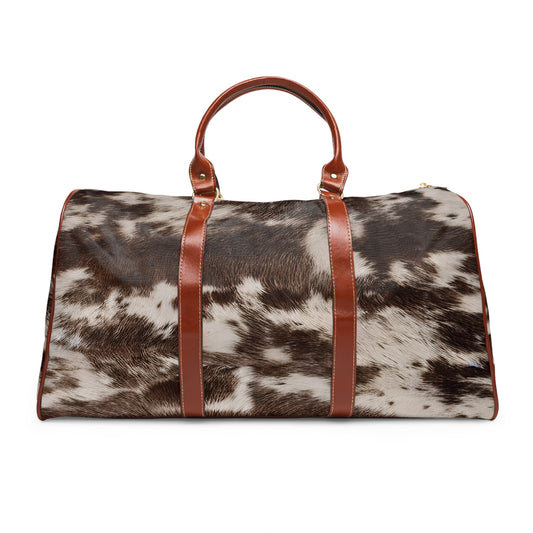 Cow Print Weekender Bag from Texas Diamond D Farms. Designed for the modern traveler with a love for unique, Western-inspired style, this bag features a striking cow print that makes it a standout piece.