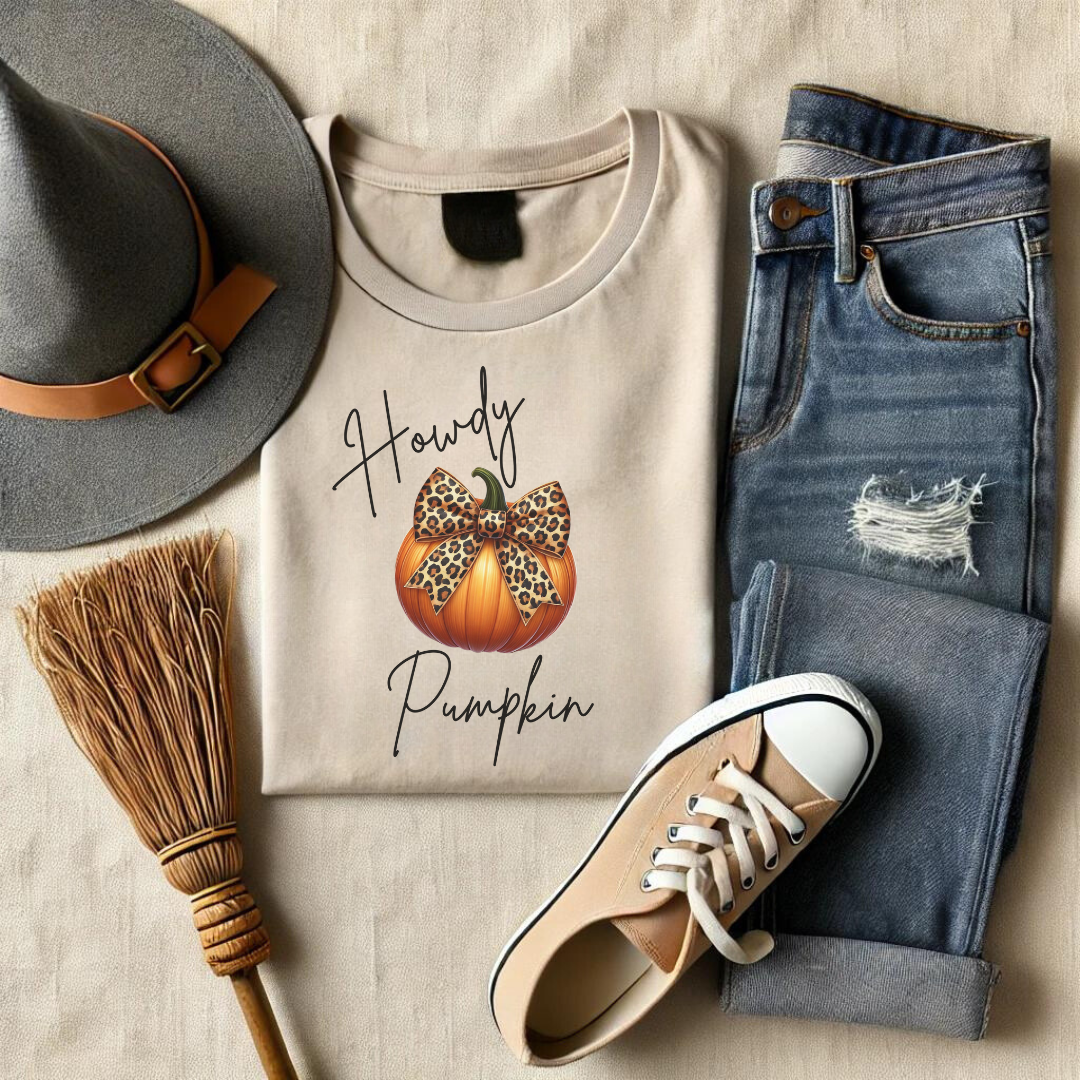 Add a touch of wild style to your fall wardrobe with our Howdy Pumpkin t-shirt! This unique design features a classic autumn pumpkin adorned with a bold leopard-print bow, perfectly blending the rustic charm of the season with a dash of fierce fashion. Whether you're heading to the pumpkin patch, enjoying a cozy fall day, or gearing up for Halloween festivities, this t-shirt is sure to turn heads.